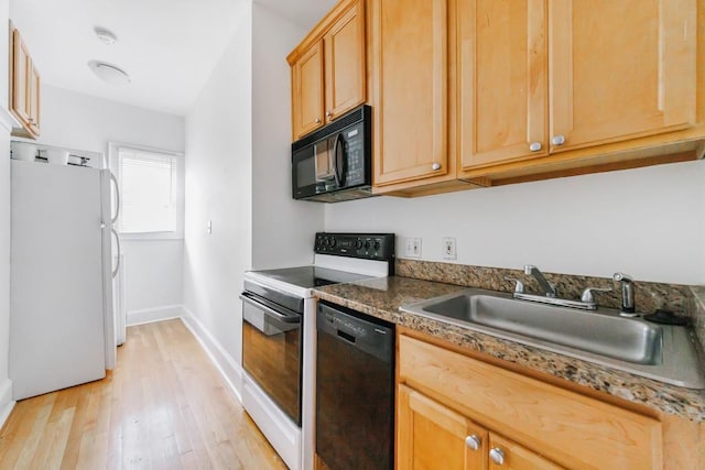 kitchen featuring black appliances, light wood-type flooring, sink, and dark stone countertops