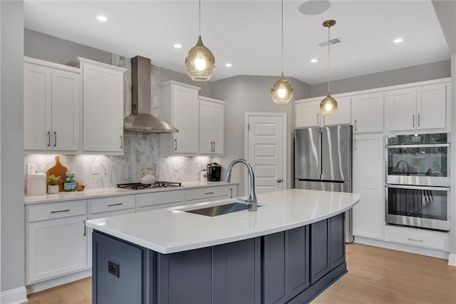 kitchen featuring white cabinetry, sink, hanging light fixtures, stainless steel appliances, and wall chimney exhaust hood