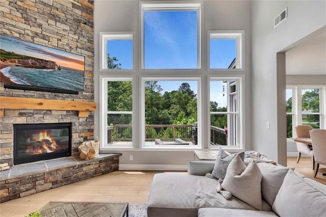 living room featuring wood-type flooring, a fireplace, and a high ceiling