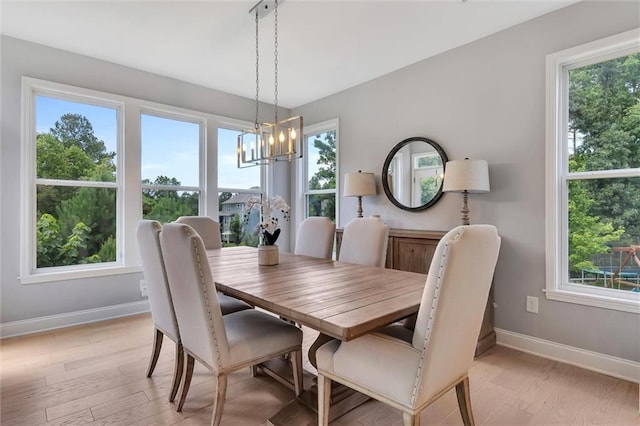 dining room with a notable chandelier, plenty of natural light, and light wood-type flooring