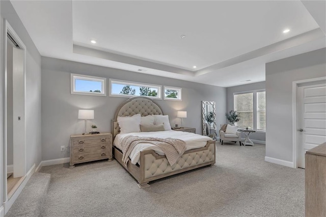 bedroom featuring multiple windows, light carpet, and a tray ceiling