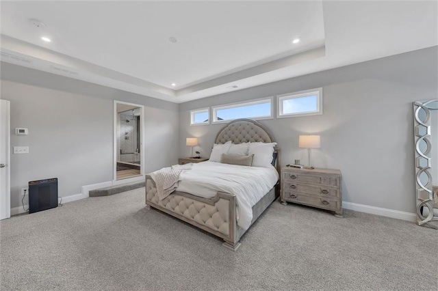 bedroom featuring connected bathroom, a raised ceiling, and light carpet