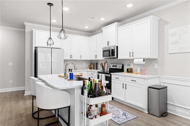 kitchen featuring white cabinetry, sink, stainless steel appliances, and a center island with sink