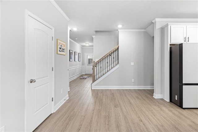 kitchen featuring white cabinetry, crown molding, refrigerator, and light hardwood / wood-style floors