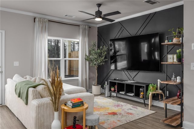 living room featuring ceiling fan, ornamental molding, and wood-type flooring