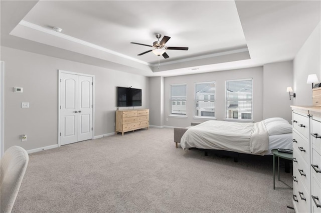 bedroom featuring a tray ceiling, light colored carpet, and ceiling fan