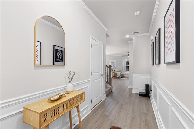 corridor with ornamental molding and light hardwood / wood-style flooring