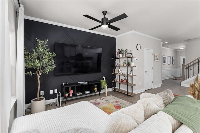 living room featuring wood-type flooring, ornamental molding, and ceiling fan