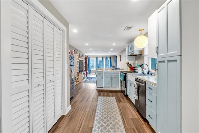 kitchen with dark wood finished floors, a peninsula, visible vents, light countertops, and stainless steel appliances