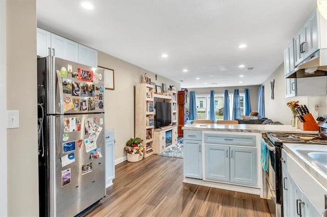 kitchen featuring recessed lighting, a peninsula, light countertops, stainless steel appliances, and wood finished floors
