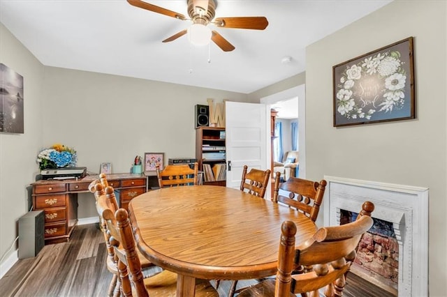 dining space featuring ceiling fan, baseboards, and dark wood-style floors