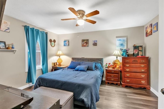 bedroom featuring wood finished floors, baseboards, and a ceiling fan