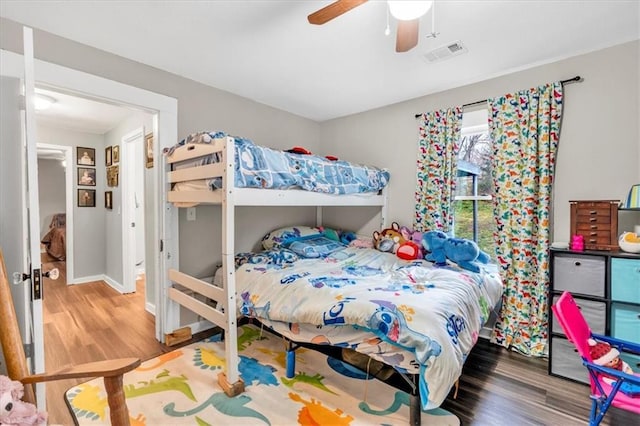 bedroom with visible vents, baseboards, a ceiling fan, and wood finished floors