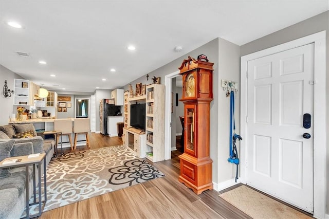living room with recessed lighting, visible vents, baseboards, and wood finished floors