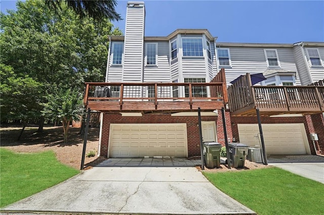 350 Eagle Tiff Dr, Sugar Hill, GA 30518 - view of front of house with a garage, driveway, a chimney, brick siding, and a wooden deck