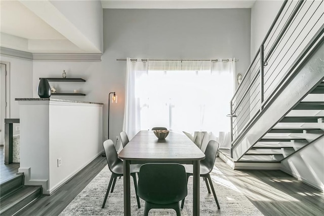 dining space with dark hardwood / wood-style floors and a towering ceiling