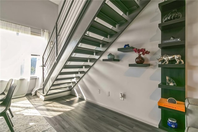 stairs with hardwood / wood-style flooring and a high ceiling