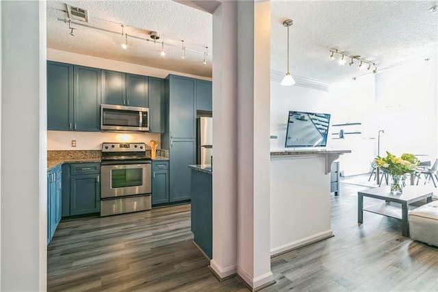 kitchen with dark wood-type flooring, pendant lighting, rail lighting, appliances with stainless steel finishes, and a textured ceiling