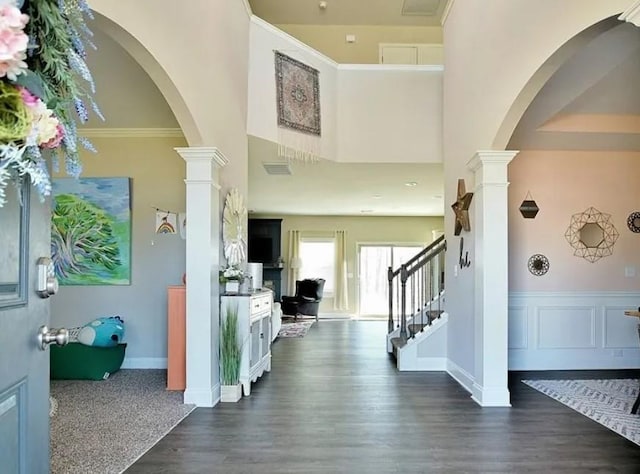 entryway featuring a high ceiling, dark hardwood / wood-style floors, crown molding, and decorative columns