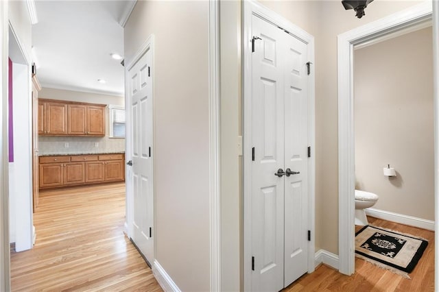 hallway with light hardwood / wood-style floors and crown molding