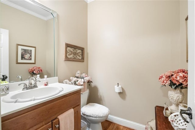 bathroom featuring ornamental molding, vanity, wood-type flooring, and toilet