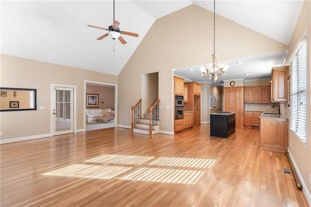 kitchen with a center island, high vaulted ceiling, decorative light fixtures, light hardwood / wood-style floors, and light stone counters