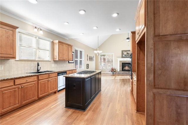 kitchen with a center island, light stone countertops, sink, and appliances with stainless steel finishes