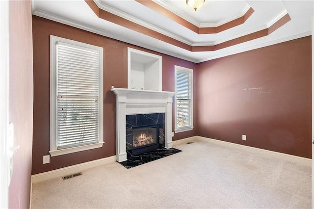 unfurnished living room with carpet, a tray ceiling, and crown molding