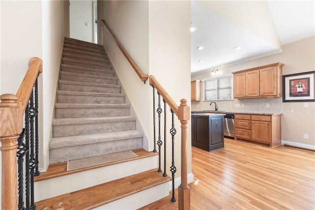 stairs with hardwood / wood-style floors, vaulted ceiling, and sink