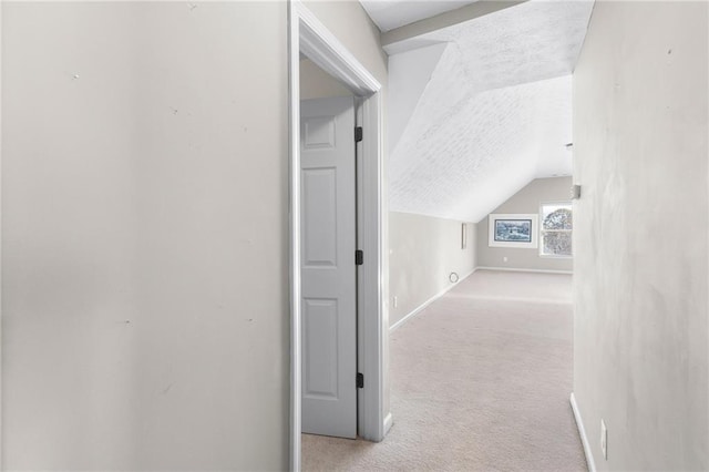 hallway with light colored carpet and lofted ceiling