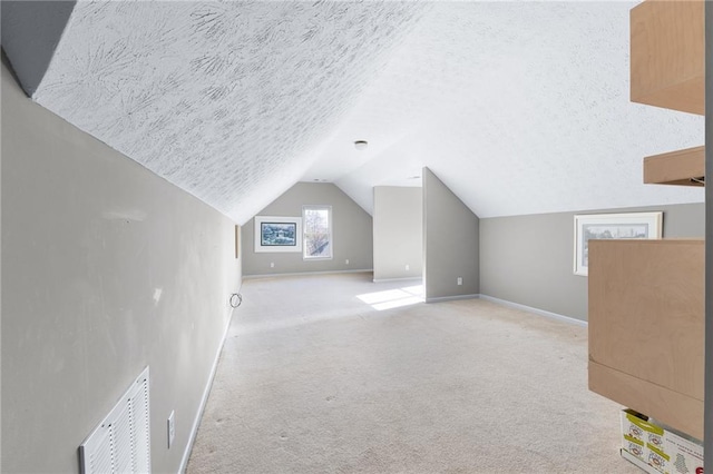 additional living space with light colored carpet, lofted ceiling, and a textured ceiling