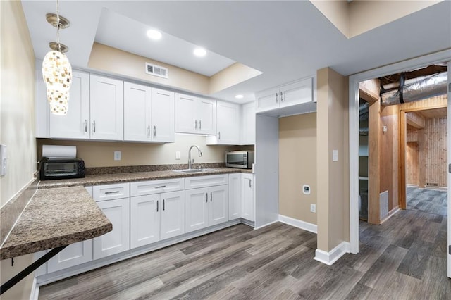 kitchen featuring white cabinets, sink, hanging light fixtures, and dark wood-type flooring