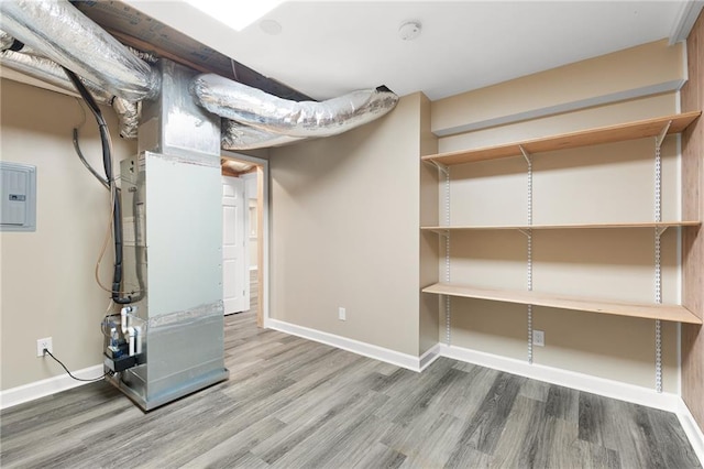 basement with hardwood / wood-style floors, electric panel, and heating unit