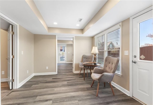 sitting room with a tray ceiling and dark hardwood / wood-style floors