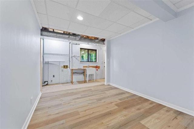 interior space featuring a drop ceiling and light wood-type flooring