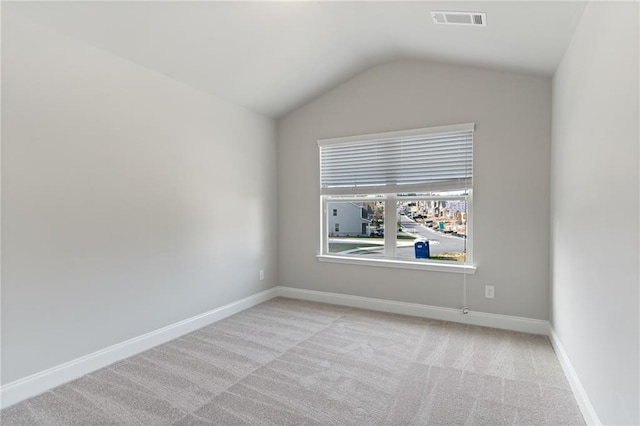 carpeted spare room featuring vaulted ceiling