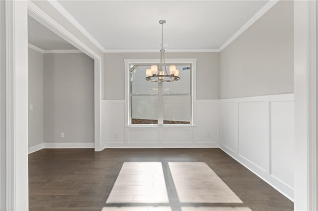 unfurnished dining area with dark wood-type flooring, ornamental molding, and an inviting chandelier