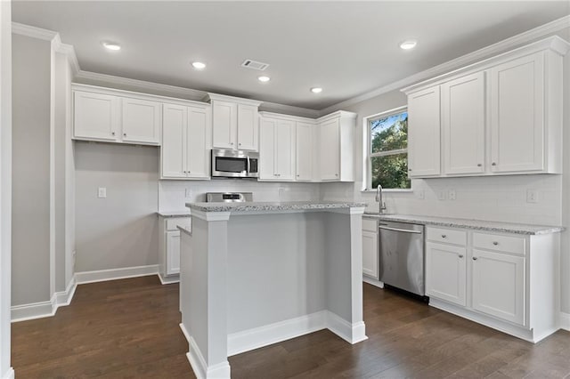 kitchen featuring dark wood-type flooring, white cabinetry, stainless steel appliances, light stone countertops, and a kitchen island