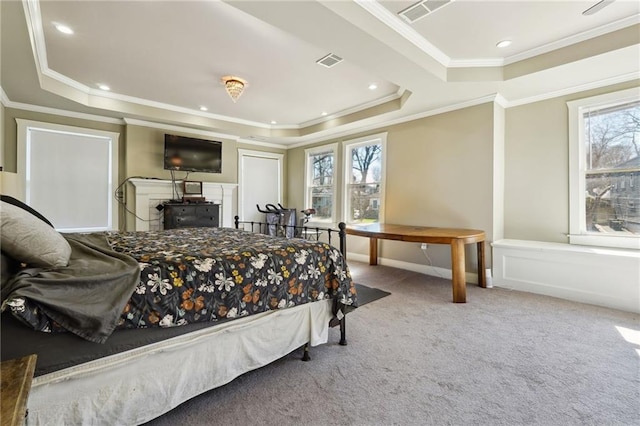 carpeted bedroom with ornamental molding and a tray ceiling