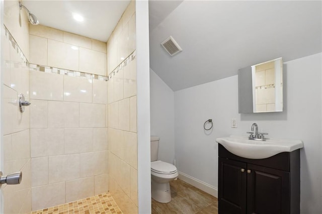 bathroom featuring toilet, vanity, and tiled shower