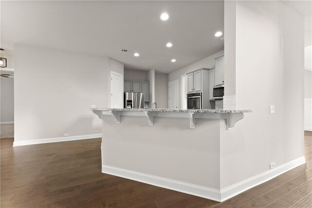 427 Dawson Pointe Pkwy, Dawsonville, GA 30534 - kitchen featuring appliances with stainless steel finishes, a kitchen bar, baseboards, dark wood-type flooring, and recessed lighting