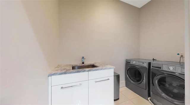 clothes washing area featuring light tile patterned floors, separate washer and dryer, a sink, and cabinet space