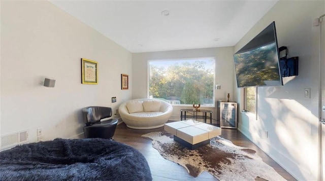 living area with baseboards, visible vents, and wood finished floors