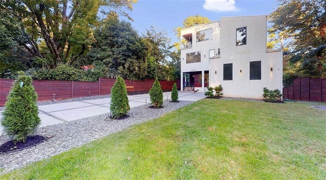 contemporary home with a front lawn, fence, and stucco siding