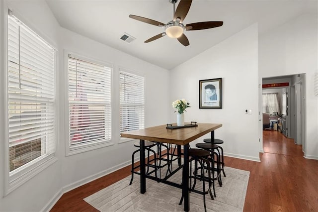 dining space with vaulted ceiling, ceiling fan, and dark wood-type flooring