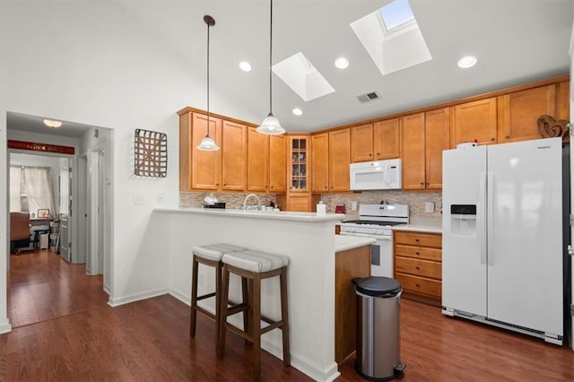 kitchen featuring pendant lighting, white appliances, decorative backsplash, dark hardwood / wood-style flooring, and kitchen peninsula