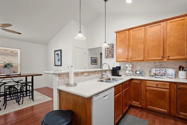 kitchen featuring kitchen peninsula, tasteful backsplash, white dishwasher, sink, and hanging light fixtures