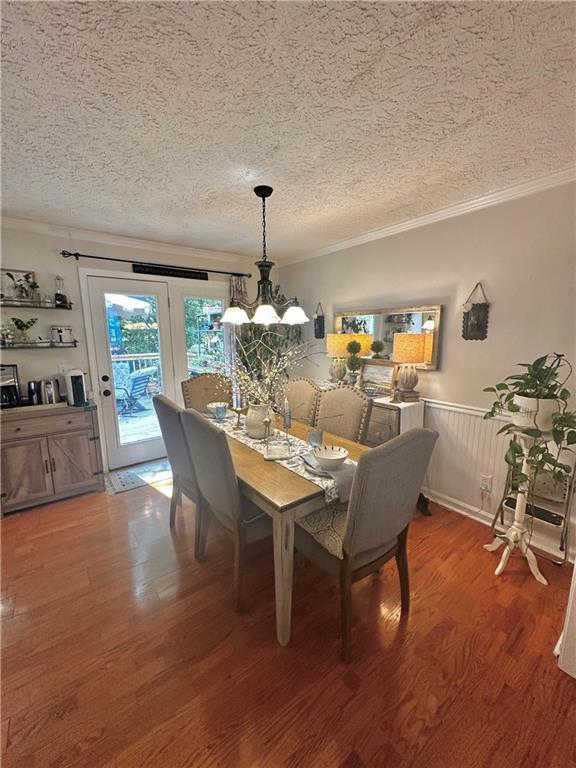 227 Bennett Farms Trl, Acworth, GA 30102 - dining room featuring ornamental molding, light wood-style floors, a textured ceiling, a wainscoted wall, and a chandelier