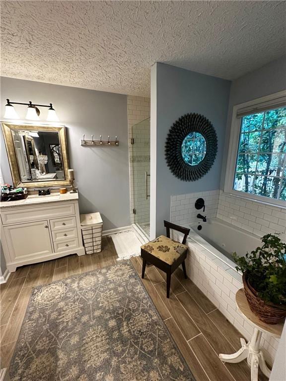 227 Bennett Farms Trl, Acworth, GA 30102 - full bath with vanity, wood tiled floors, a bath, a shower stall, and a textured ceiling