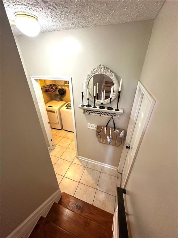 227 Bennett Farms Trl, Acworth, GA 30102 - stairs with washing machine and clothes dryer, tile patterned flooring, and a textured ceiling